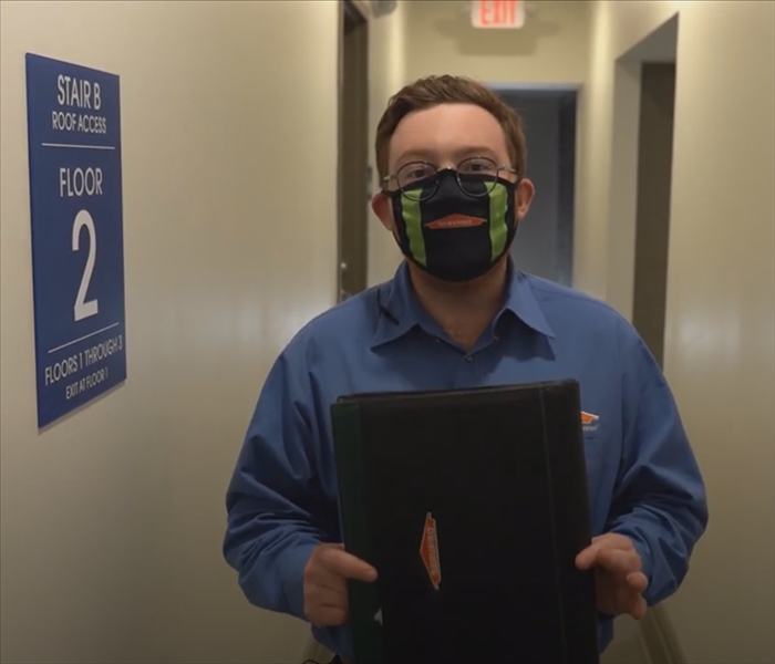 Dan from SERVPRO standing in a hallway with a padfolio.
